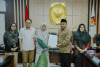 Anggota Bawaslu Kota Samarinda, Sugeng Prasetyo (mengenakan baju batik cokelat dan peci), menerima secara langsung salinan Berita Acara Hasil Rekapitulasi Daftar Pemilih Berkelanjutan (PDPB) Triwulan III Tahun 2026 usai Rapat Pleno Terbuka di Kantor KPU Kota Samarinda, Rabu (30/9/2026).